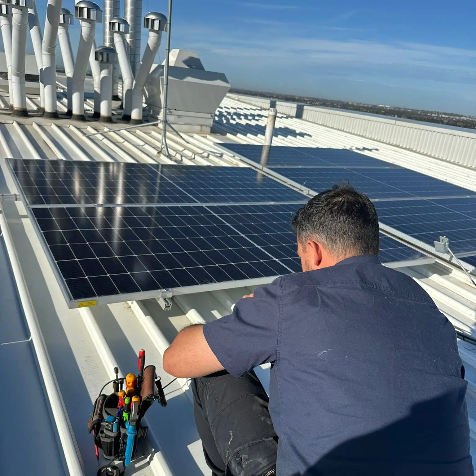 Technician checking an existing rooftop solar array during a system health check